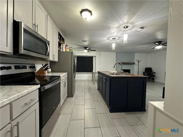 kitchen featuring sink, white cabinets, stainless steel appliances, and a center island with sink