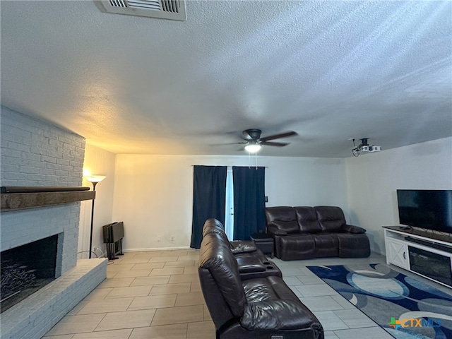 living room featuring ceiling fan, a fireplace, and a textured ceiling