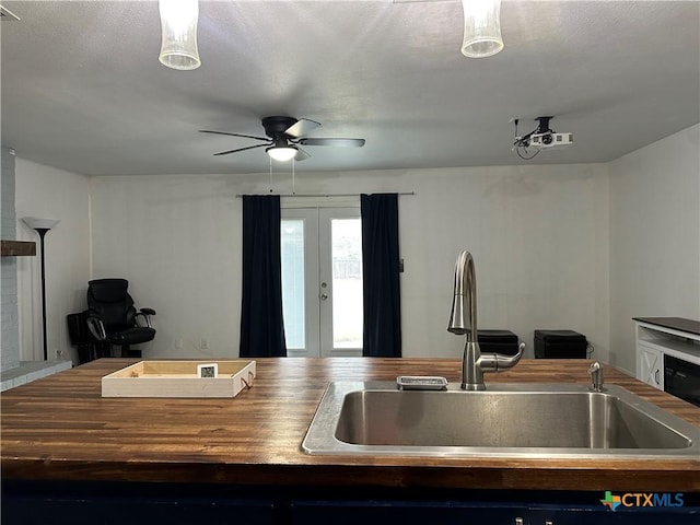 kitchen with pendant lighting, french doors, sink, ceiling fan, and a textured ceiling