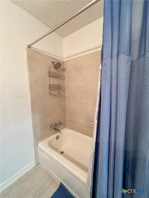 bathroom featuring wood-type flooring, a textured ceiling, and shower / bath combo with shower curtain