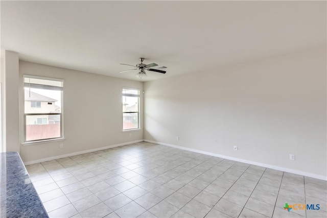 spare room with a ceiling fan, light tile patterned floors, and baseboards