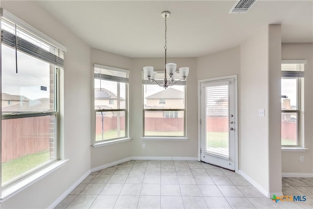 unfurnished dining area with a chandelier, plenty of natural light, light tile patterned flooring, and baseboards