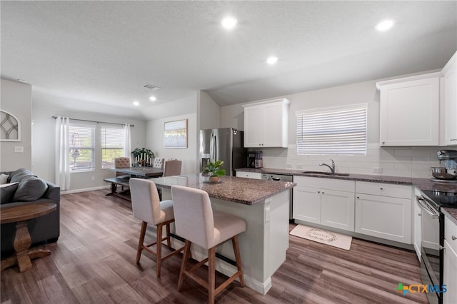 6038 Ballast Trl, New Braunfels, TX 78132 - kitchen featuring stainless steel appliances, a sink, a kitchen island, a breakfast bar, and wood finished floors