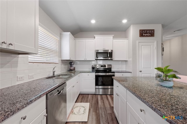 6038 Ballast Trl, New Braunfels, TX 78132 - kitchen with appliances with stainless steel finishes, a sink, white cabinets, dark stone counters, and vaulted ceiling