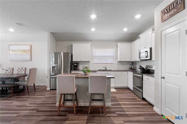 6038 Ballast Trl, New Braunfels, TX 78132 - kitchen with stainless steel appliances, a sink, a kitchen island, dark wood finished floors, and recessed lighting