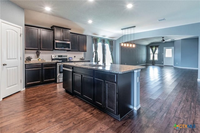 kitchen featuring a center island with sink, decorative light fixtures, sink, appliances with stainless steel finishes, and dark hardwood / wood-style floors