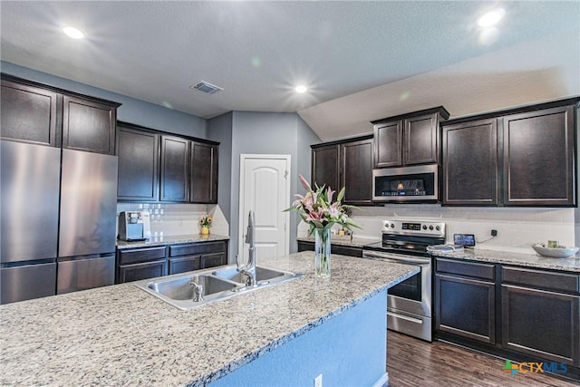 kitchen featuring dark brown cabinets, dark wood-type flooring, stainless steel appliances, decorative backsplash, and sink