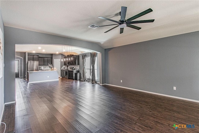 unfurnished living room featuring ceiling fan, vaulted ceiling, dark hardwood / wood-style flooring, and a textured ceiling