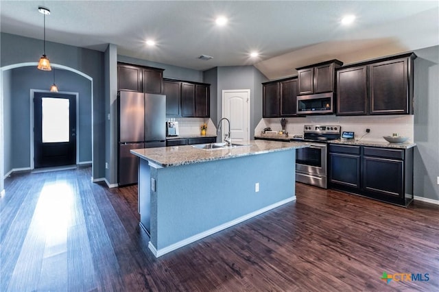 kitchen featuring appliances with stainless steel finishes, hanging light fixtures, light stone countertops, sink, and a kitchen island with sink