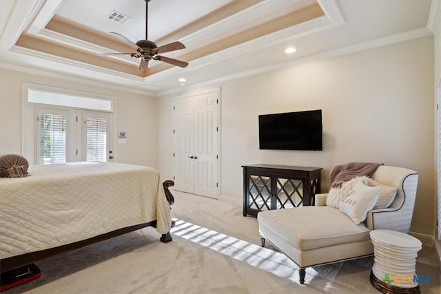 carpeted bedroom featuring a raised ceiling, ceiling fan, crown molding, and a closet