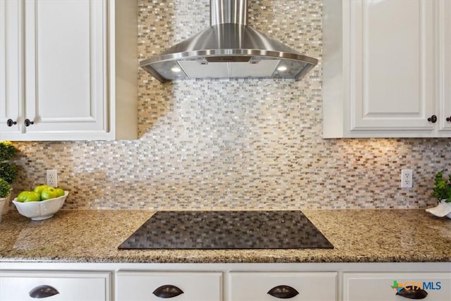 kitchen featuring black electric cooktop, white cabinets, wall chimney exhaust hood, and decorative backsplash