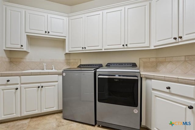 laundry room featuring sink, cabinets, washing machine and clothes dryer, and light tile patterned floors