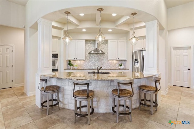 kitchen with white cabinets, decorative light fixtures, light stone counters, and decorative columns