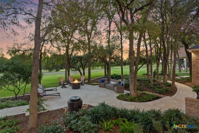 view of property's community with a fire pit, a patio, and a lawn