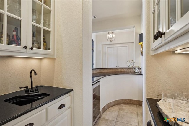 kitchen featuring sink, white cabinets, light tile patterned floors, pendant lighting, and wine cooler