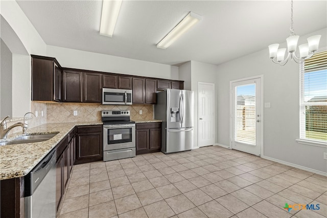 kitchen featuring sink, backsplash, a chandelier, light tile patterned flooring, and appliances with stainless steel finishes