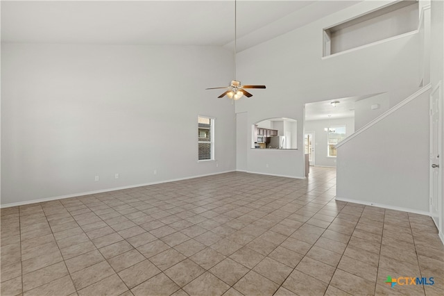 unfurnished living room featuring ceiling fan, plenty of natural light, high vaulted ceiling, and light tile patterned floors