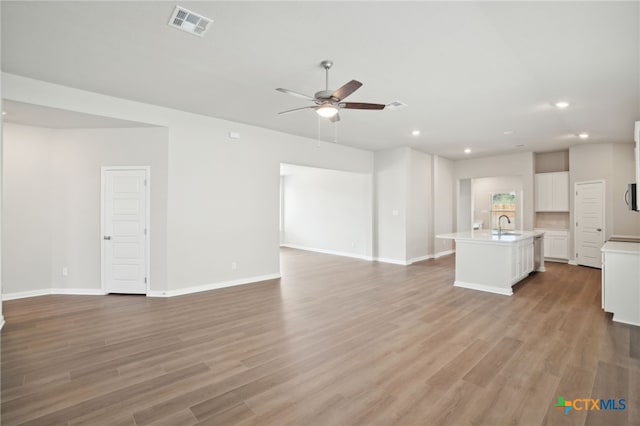 unfurnished living room with ceiling fan, light hardwood / wood-style flooring, and sink