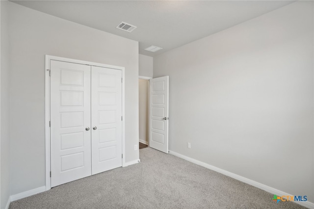 unfurnished bedroom featuring a closet and light colored carpet