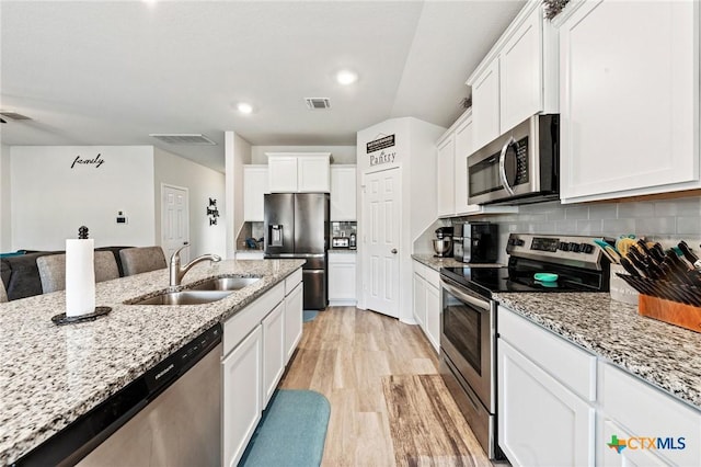 kitchen with tasteful backsplash, visible vents, stainless steel appliances, light wood-style floors, and a sink