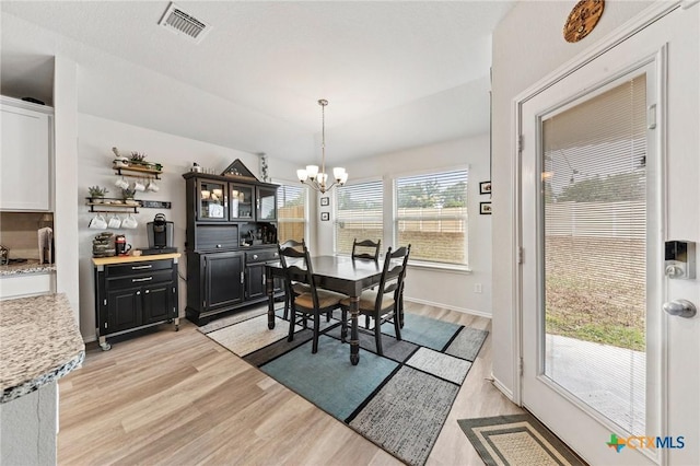 dining room featuring light wood finished floors, visible vents, and a chandelier