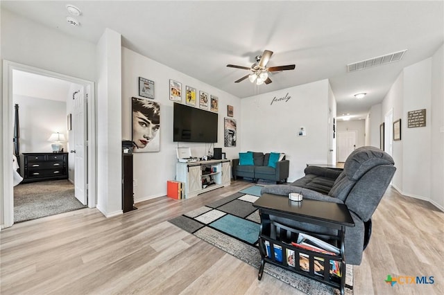 living room featuring ceiling fan, light wood finished floors, visible vents, and baseboards