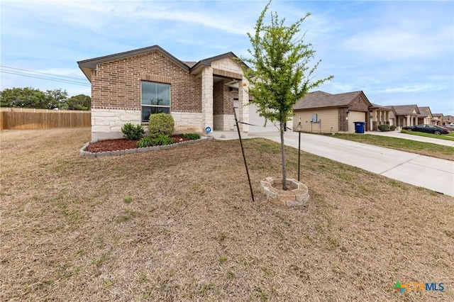 view of front of house with driveway, stone siding, fence, a front lawn, and brick siding