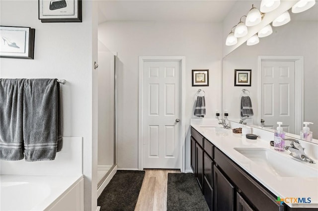 bathroom featuring double vanity, a stall shower, and a sink