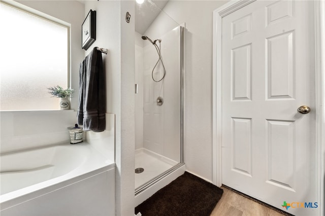 bathroom featuring a stall shower, wood finished floors, and a bath