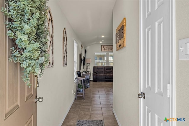 hall featuring vaulted ceiling and tile patterned floors