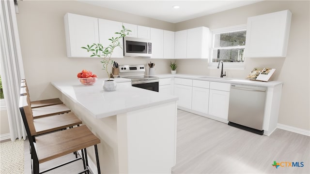 kitchen with a kitchen breakfast bar, a sink, range with electric stovetop, dishwasher, and stainless steel microwave