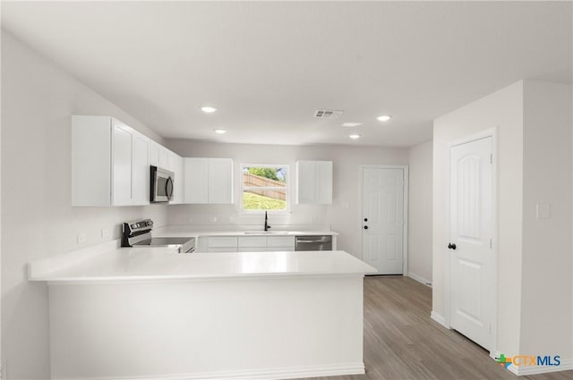3815 Leming Ct, Temple, TX 76504 - kitchen featuring appliances with stainless steel finishes, light wood-style floors, a peninsula, light countertops, and recessed lighting