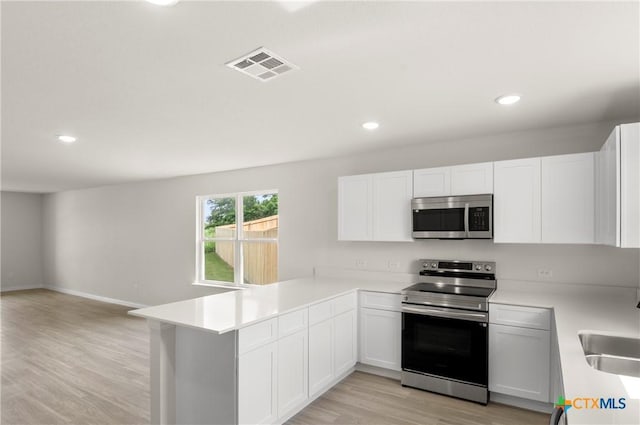 3815 Leming Ct, Temple, TX 76504 - kitchen with appliances with stainless steel finishes, light wood-type flooring, light countertops, a peninsula, and open floor plan
