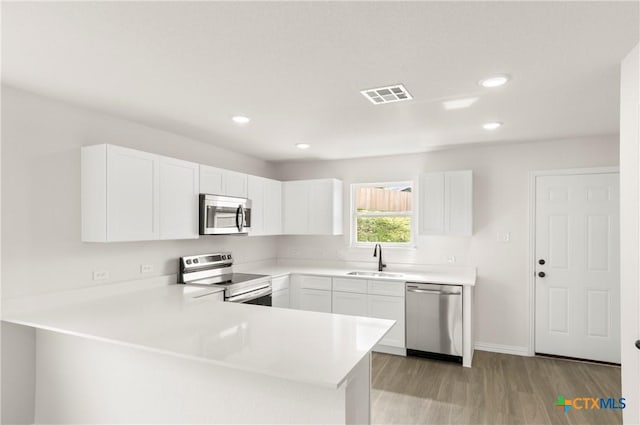 3815 Leming Ct, Temple, TX 76504 - kitchen featuring appliances with stainless steel finishes, light wood-style flooring, a peninsula, white cabinets, and recessed lighting