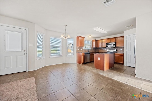 4805 Farrell Ln, Killeen, TX 76549 - kitchen featuring appliances with stainless steel finishes, decorative backsplash, light tile patterned floors, a chandelier, and a kitchen island