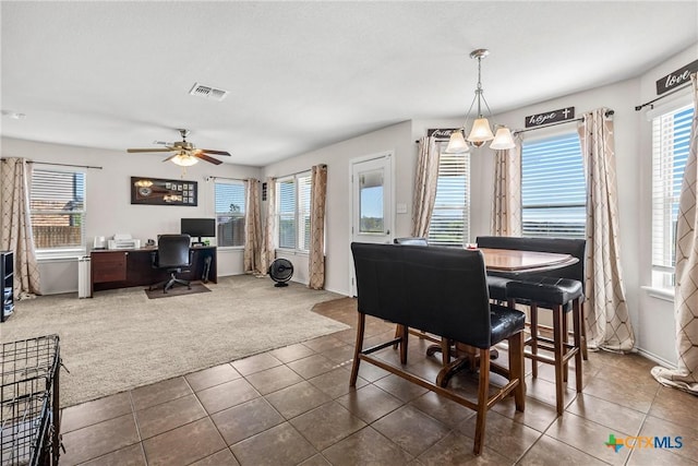 dining room with visible vents, dark tile patterned floors, plenty of natural light, and dark colored carpet