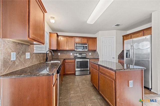 4805 Farrell Ln, Killeen, TX 76549 - kitchen with appliances with stainless steel finishes, a kitchen island, dark stone countertops, decorative backsplash, and brown cabinets