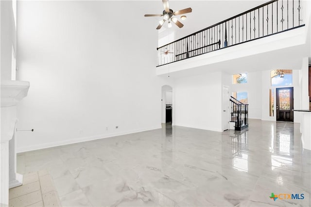 unfurnished living room with a high ceiling and ceiling fan