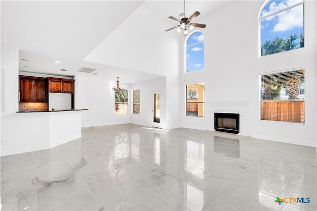 unfurnished living room with ceiling fan and a towering ceiling