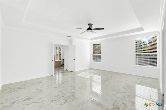 empty room with a raised ceiling and ceiling fan