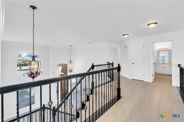 corridor featuring light wood-type flooring and an inviting chandelier