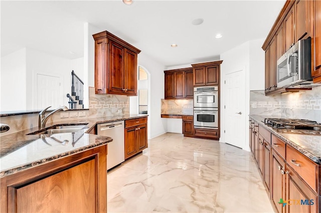 kitchen with light stone countertops, appliances with stainless steel finishes, decorative backsplash, and sink