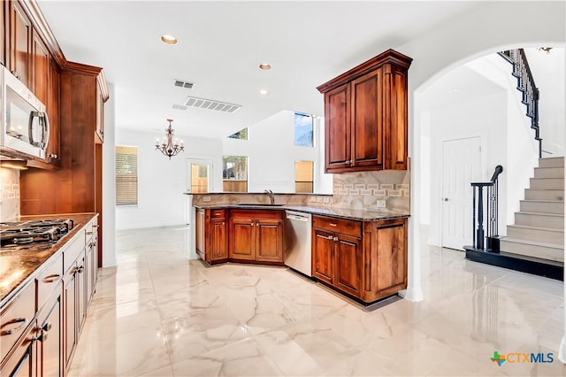 kitchen featuring appliances with stainless steel finishes, a notable chandelier, pendant lighting, sink, and tasteful backsplash