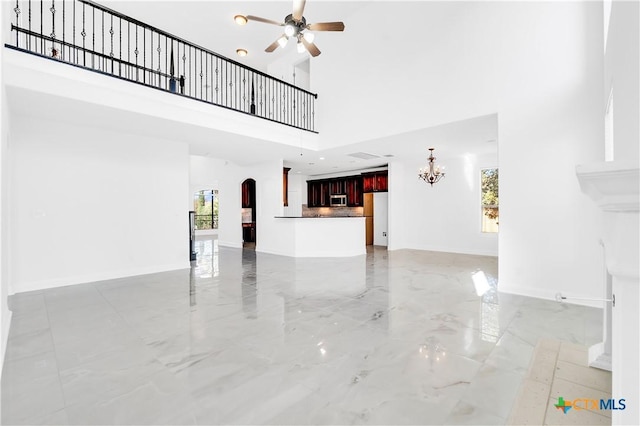 unfurnished living room with a high ceiling, ceiling fan, and a healthy amount of sunlight