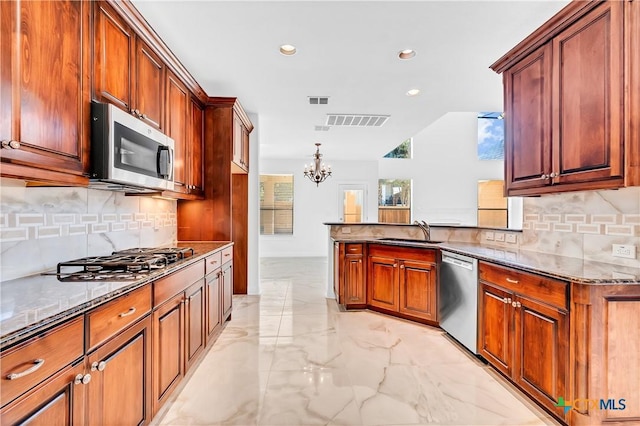 kitchen featuring a chandelier, stainless steel appliances, light stone counters, decorative backsplash, and sink