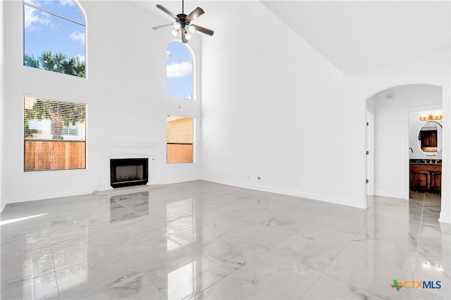 unfurnished living room with a towering ceiling and ceiling fan