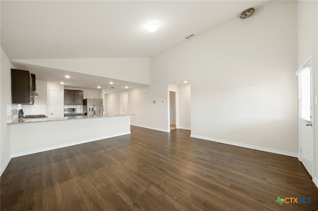 unfurnished living room featuring dark wood-type flooring and high vaulted ceiling