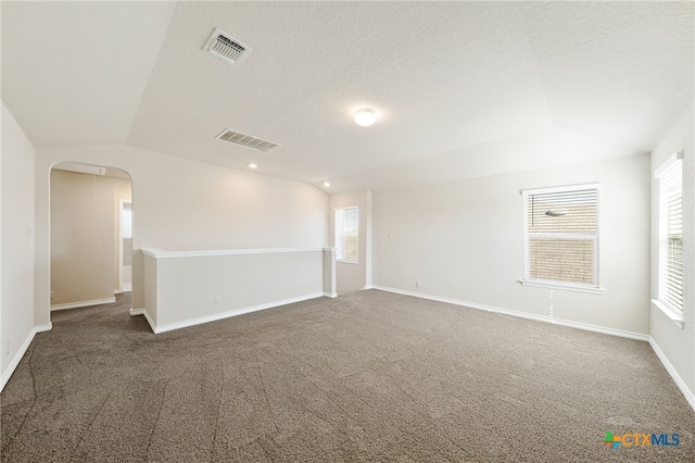 carpeted spare room with a textured ceiling and vaulted ceiling