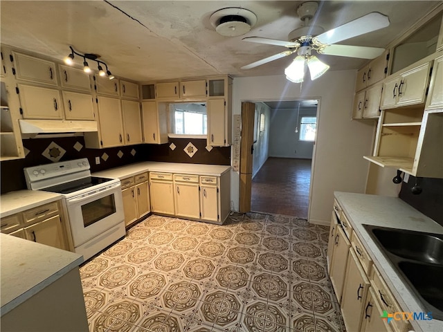 kitchen with a wealth of natural light, white range with electric cooktop, ceiling fan, and tasteful backsplash