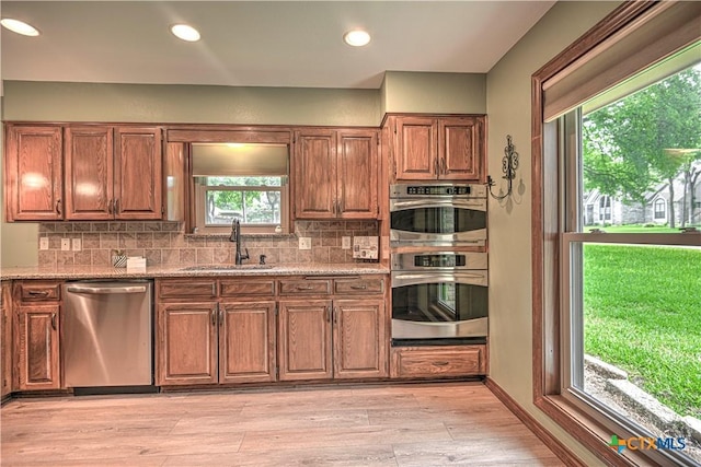 2702 Olympia Dr, Temple, TX 76502 - kitchen featuring appliances with stainless steel finishes, backsplash, light stone countertops, light wood finished floors, and recessed lighting